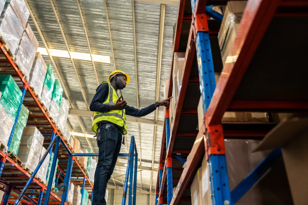 Warehouse worker inspecting electronics inventory on industrial storage racks